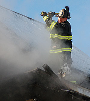 Lt. Tom Tierney opens up the roof at 81 Mt. Vernon Street to get ahead of fire spreading in the roof area.