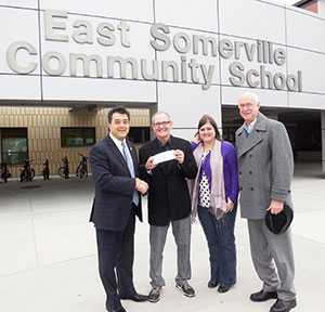 (L to R) Attorney Philip J. Privitera, presents $1000 Angel Fund Donation from Arlington's Mystic Valley Lodge of Freemasons to Jean DeVanthery, at the East Somerville Community School, while the School's Counselor on Education, Carlie Calioro, and Ted Wilson of Dearborn Academy in Arlington stand by.
